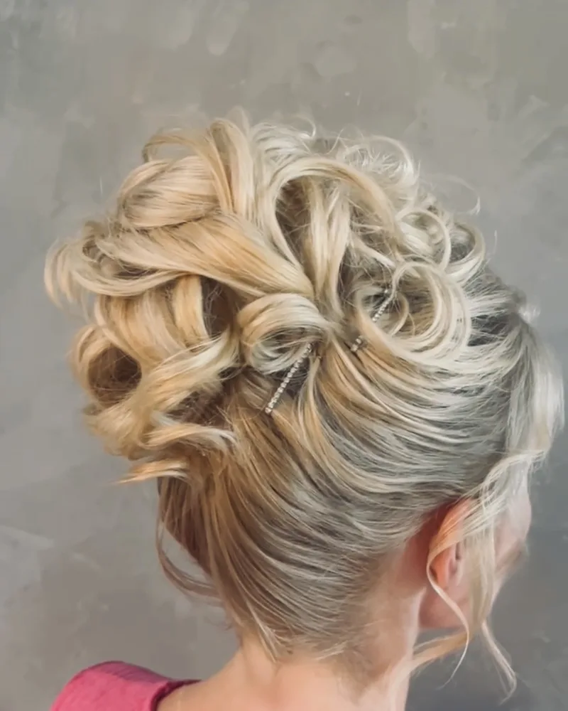Curled blonde updo with a decorative hair pin