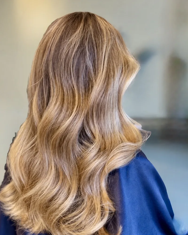 Honey blonde balayage with soft waves on long hair